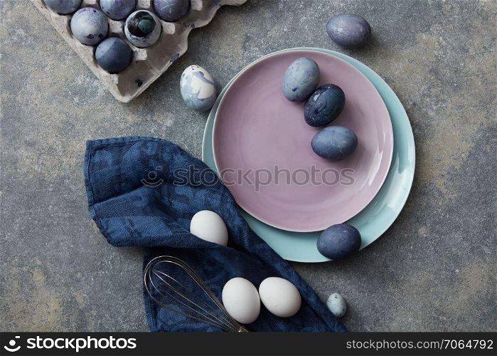Easter eggs on a plate with napkin and paper tray on a stone background. Easter eggs on a plate