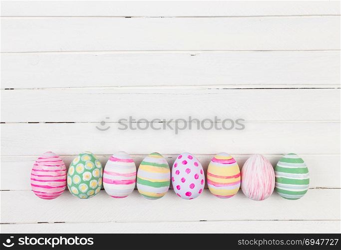 Easter eggs painted in pastel colors on a white wood background