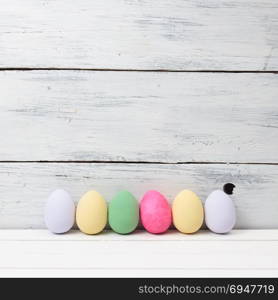 Easter eggs painted in pastel colors on white wooden background