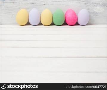 Easter eggs painted in pastel colors on white wooden background