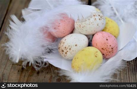 easter eggs painted in white feathers on wooden background
