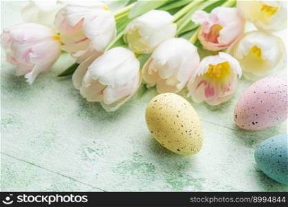  Easter eggs painted pastel colors and pink tulips on a green wooden background.  Top view. Space for text. 