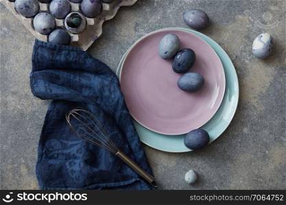 Easter eggs with blue cloth and whisk on stone background. Colorful easter eggs