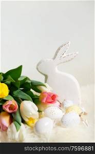 Easter eggs with bunny and fresh tulips bouquet close up. Easter scene with colored eggs