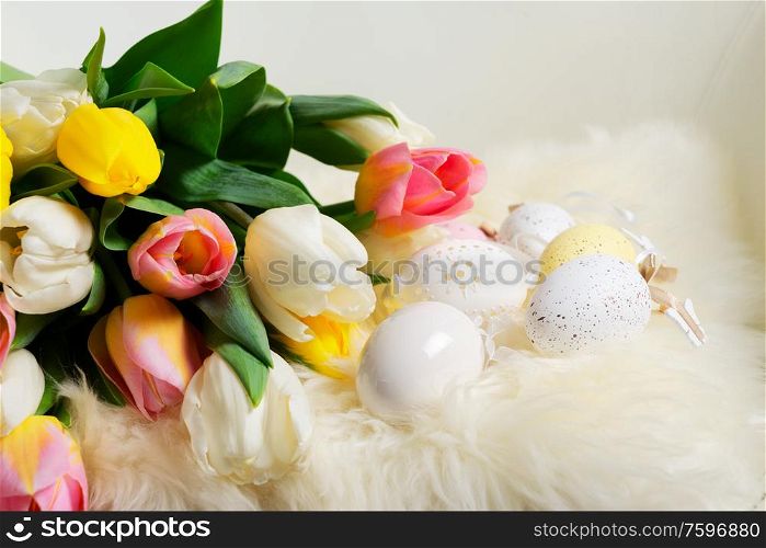 Easter eggs with fresh tulip flowers bouquet. Easter scene with colored eggs