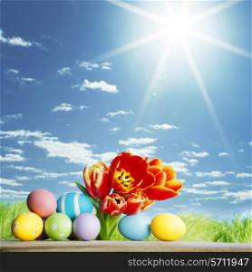 Easter eggs with tulips on spring grass background