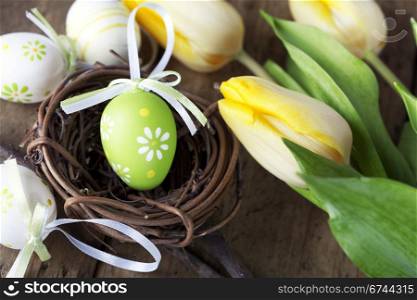 easter eggs with yellow tulip flowers isolated on wooden board