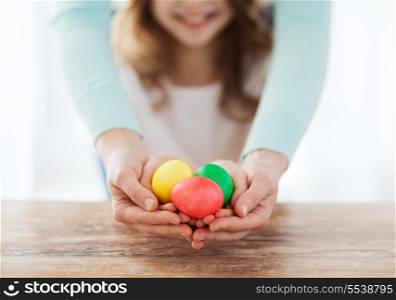 easter, family, holiday and child concept - close up of little girl and mother holding colored eggs