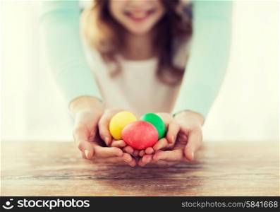 easter, family, holiday and child concept - close up of little girl and mother holding colored eggs