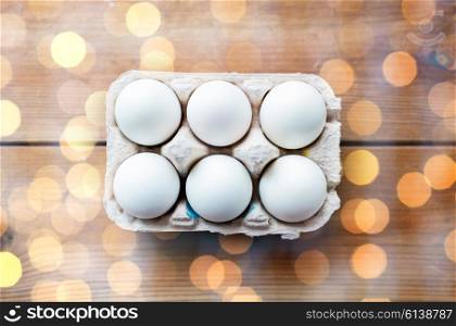 easter, food, cooking and object concept - close up of white eggs in egg box or carton wooden surface
