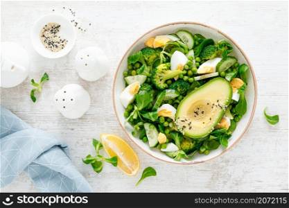 Easter fresh vegetable salad with boiled egg, broccoli, corn salad, green peas and avocado, top view