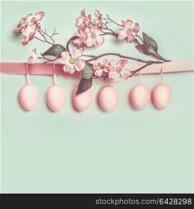 Easter greeting card layout with hanging pastel pink eggs and beautiful spring blossom decoration, copy space for your design, text, greeting or invitation