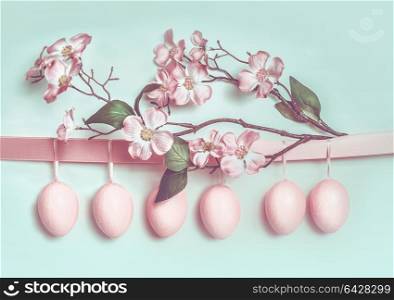 Easter greeting card with hanging pastel pink eggs, ribbon and beautiful spring blossom decoration