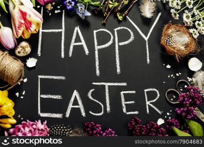 Easter greetings on a blackboard with eggs, flowers and nest