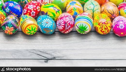 Easter handmade eggs painted in colorful floral patterns placed on wooden table.. Easter handmade eggs on wooden table.