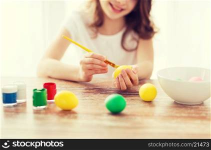 easter, holiday and child concept - close up of girl coloring eggs for easter