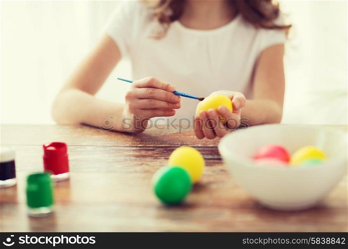 easter, holiday and child concept - close up of girl coloring eggs for easter