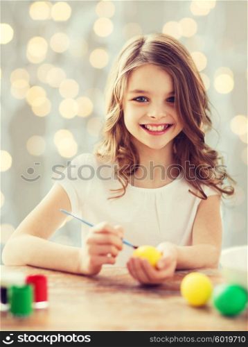 easter, holiday and child concept - close up of girl with brush coloring easter eggs over lights background