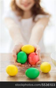 easter, holiday and child concept - close up of little girl holding colored eggs