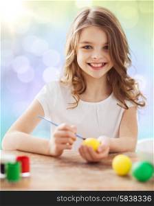 easter, holiday and child concept - happy girl with brush coloring easter eggs over lights background
