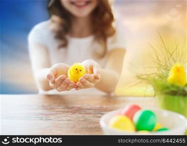 easter, holiday and people concept - close up of girl holding toy chicken over sky background. close up of girl holding easter toy chicken
