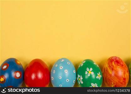 Easter holiday background. Coloured decorated easter eggs on a bright yellow background