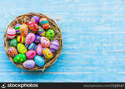 Easter holiday concept,Colorful Easter eggs in basket on blue pastel color rustic wood background with space.