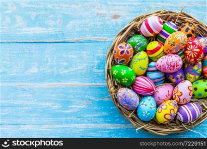 Easter holiday concept,Colorful Easter eggs in basket on blue pastel color rustic wood background with space.