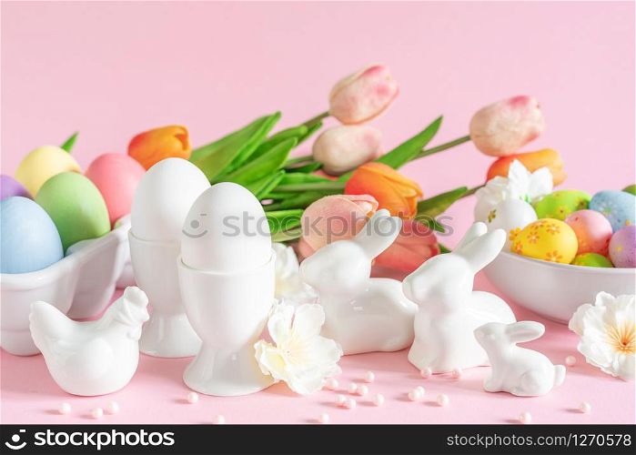 Easter holiday decorations on pink background with spring flowers, festive greeting card