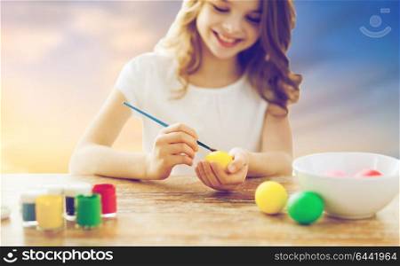 easter, holiday tradition and child concept - close up of girl coloring eggs over sky background. close up of girl coloring easter eggs