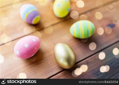 easter, holiday tradition and object concept - close up of colored eggs on wooden boards. close up of colored easter eggs on wooden boards