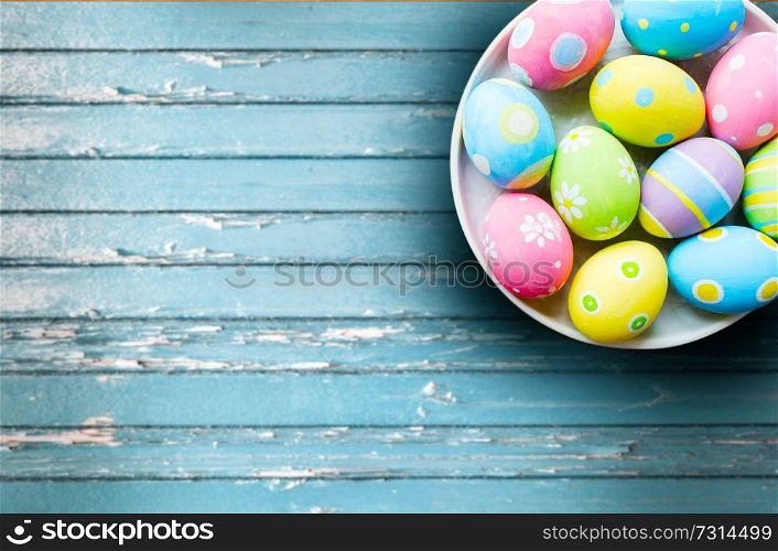 easter, holidays and object concept - close up of colored eggs on plate over blue vintage wooden boards background. close up of colored easter eggs on plate