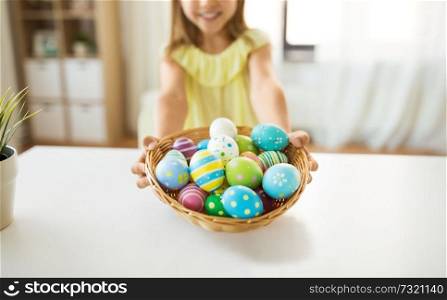 easter, holidays and people concept - close up of girl with colored eggs in wicker basket. close up of girl with easter eggs in wicker basket