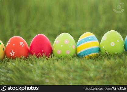easter, holidays and tradition concept - row of colored eggs on artificial grass. row of colored easter eggs on artificial grass