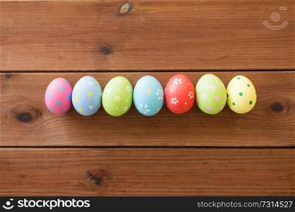 easter, holidays and tradition concept - row of colored eggs on wooden table. row of colored easter eggs on wooden table