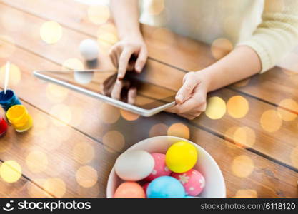 easter, holidays, technology and people concept - close up of woman hands with tablet pc computer, easter eggs and colors