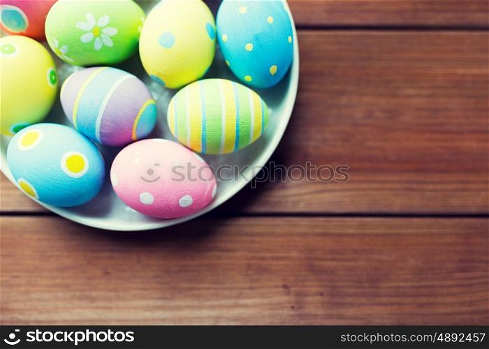 easter, holidays, tradition, advertisement and object concept - close up of colored easter eggs on plate