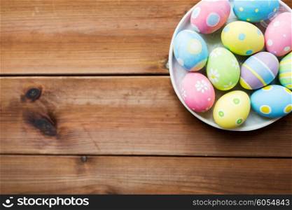 easter, holidays, tradition, advertisement and object concept - close up of colored easter eggs on plate