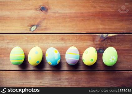 easter, holidays, tradition and object concept - close up of colored easter eggs on wooden surface with copy space
