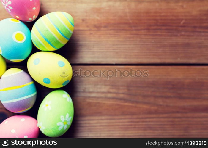 easter, holidays, tradition and object concept - close up of colored easter eggs on wooden surface with copy space