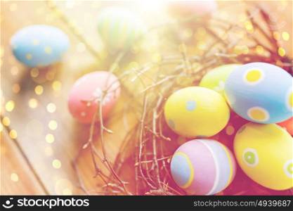 easter, holidays, tradition and object concept - close up of colored easter eggs in nest on wooden surface. close up of colored easter eggs in nest on wood