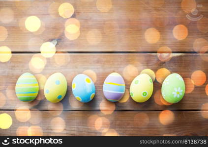 easter, holidays, tradition and object concept - close up of colored easter eggs on wooden surface with copy space