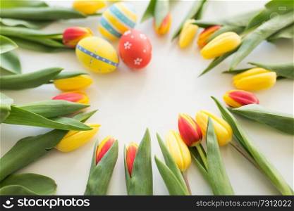 easter, holidays, tradition and object concept - close up of colored easter eggs and tulip flowers on white background. close up of colored easter eggs and tulip flowers