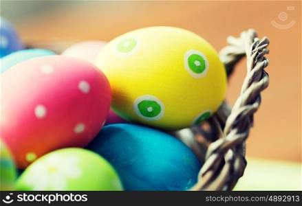 easter, holidays, tradition and object concept - close up of colored easter eggs in basket