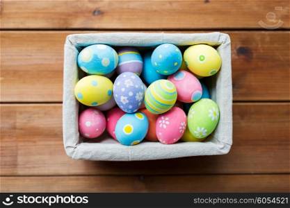 easter, holidays, tradition and object concept - close up of colored easter eggs in basket