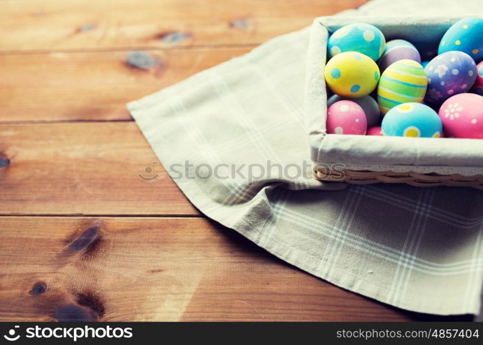 easter, holidays, tradition and object concept - close up of colored easter eggs in wicker basket