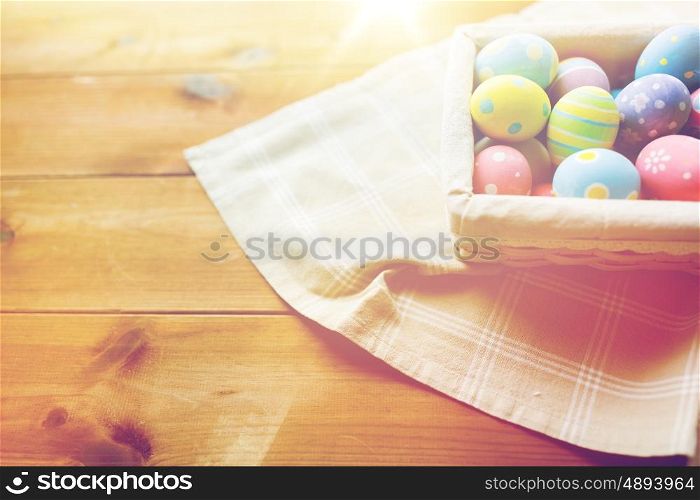 easter, holidays, tradition and object concept - close up of colored easter eggs in wicker basket