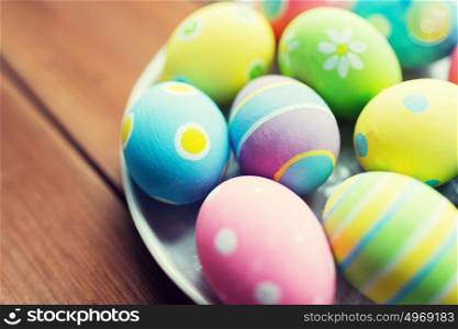 easter, holidays, tradition and object concept - close up of colored easter eggs on plate. close up of colored easter eggs on plate