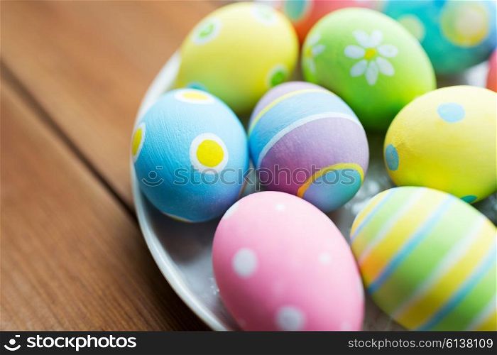 easter, holidays, tradition and object concept - close up of colored easter eggs on plate