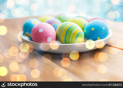 easter, holidays, tradition and object concept - close up of colored easter eggs on plate